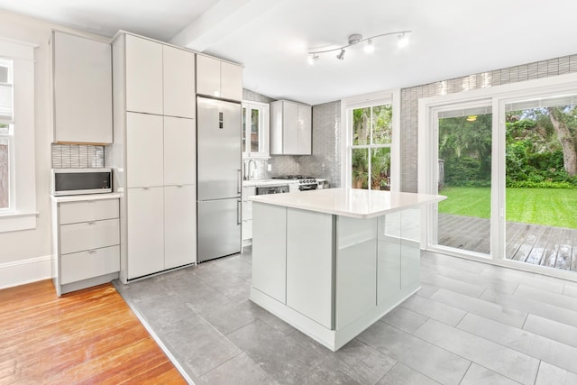 kitchen with built in fridge, white cabinetry, a kitchen island, and tasteful backsplash