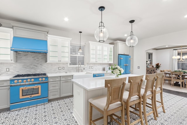 kitchen featuring extractor fan, sink, hanging light fixtures, a kitchen island, and stove