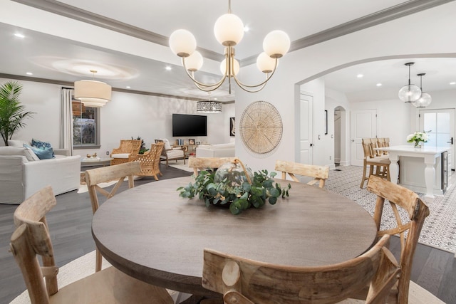 dining area with dark wood-type flooring, ornamental molding, and a notable chandelier