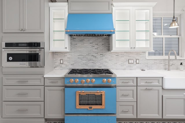 kitchen with sink, backsplash, ventilation hood, gas range oven, and oven