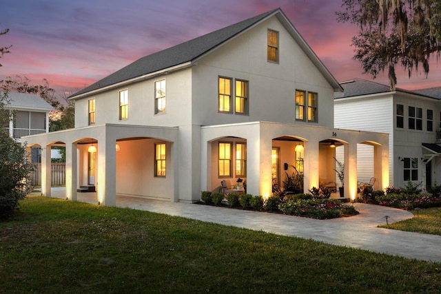 rear view of property with a yard, a patio, and stucco siding