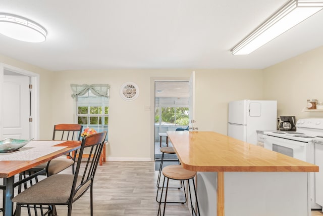 kitchen with light wood-type flooring, white appliances, white cabinets, and a wealth of natural light