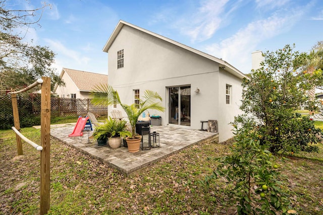 rear view of property featuring a patio area, fence, and stucco siding