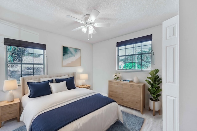 bedroom with ceiling fan, light wood-type flooring, and a textured ceiling