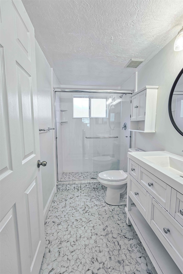 bathroom featuring vanity, visible vents, a stall shower, a textured ceiling, and toilet