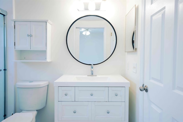 bathroom featuring toilet, vanity, and a ceiling fan