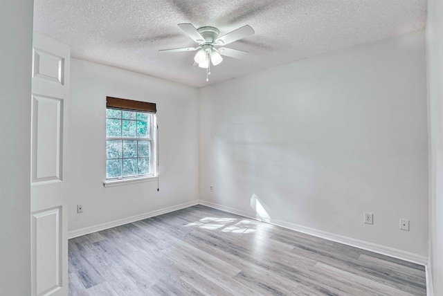 empty room with a textured ceiling, baseboards, light wood-type flooring, and a ceiling fan