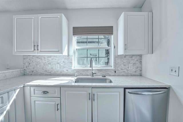 kitchen with tasteful backsplash, white cabinets, dishwasher, and a sink