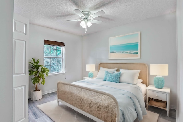 bedroom with baseboards, a textured ceiling, a ceiling fan, and wood finished floors