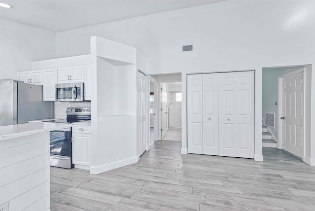 kitchen featuring wood finish floors, white cabinets, visible vents, and stainless steel appliances