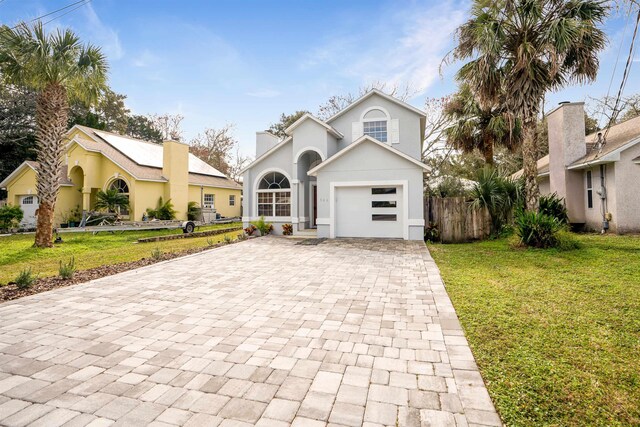 view of front facade featuring a front yard, decorative driveway, fence, and stucco siding