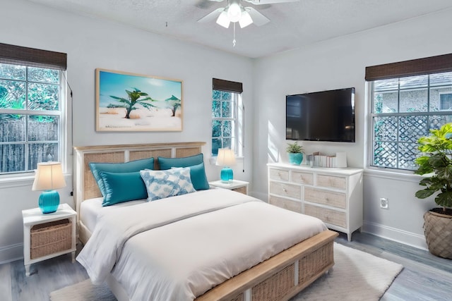 bedroom featuring ceiling fan, wood finished floors, baseboards, and a textured ceiling