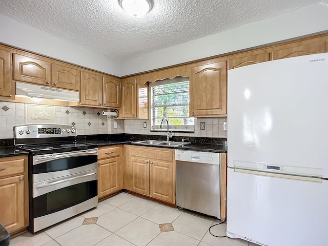 kitchen with stainless steel appliances, sink, light tile patterned floors, and a textured ceiling