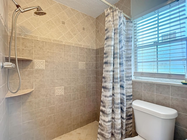 bathroom featuring tile walls, curtained shower, toilet, and a textured ceiling