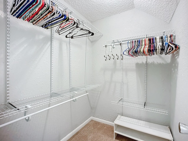 spacious closet with vaulted ceiling and carpet flooring