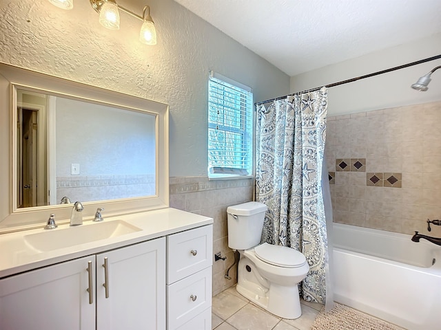 full bathroom with tile walls, vanity, a textured ceiling, tile patterned floors, and shower / bath combo with shower curtain