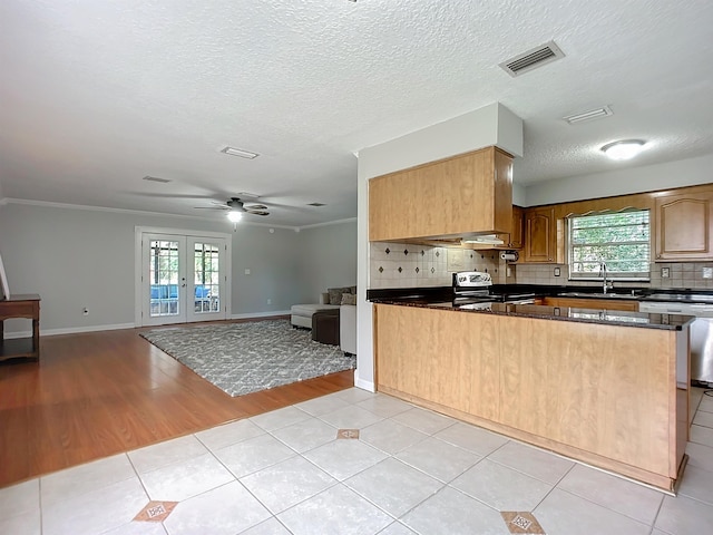 kitchen with a wealth of natural light, light tile patterned floors, kitchen peninsula, stainless steel appliances, and french doors