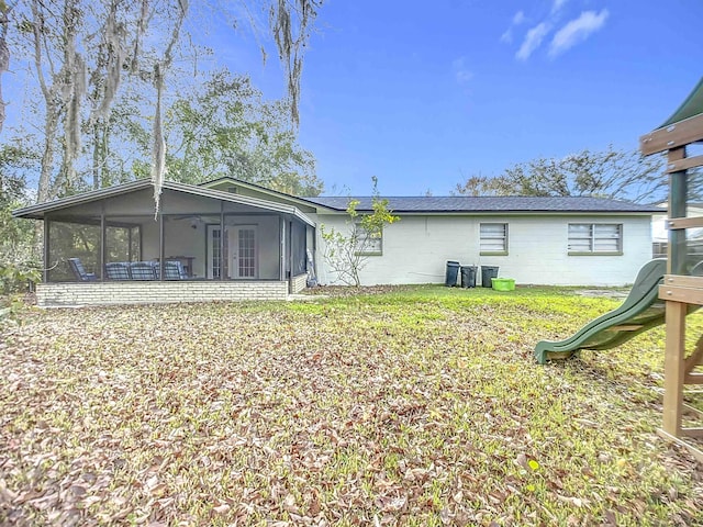 rear view of property with a yard, a playground, and a sunroom