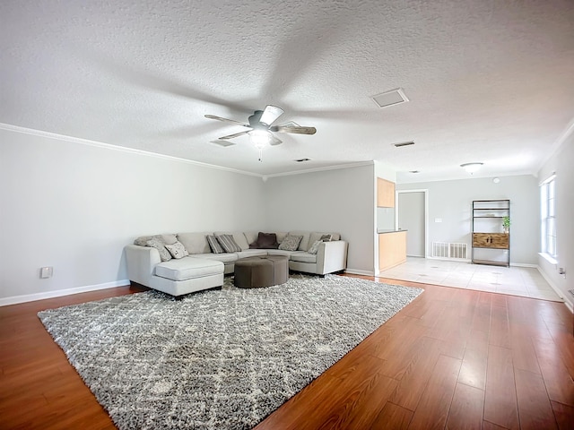 living room featuring ceiling fan, ornamental molding, light hardwood / wood-style flooring, and a textured ceiling