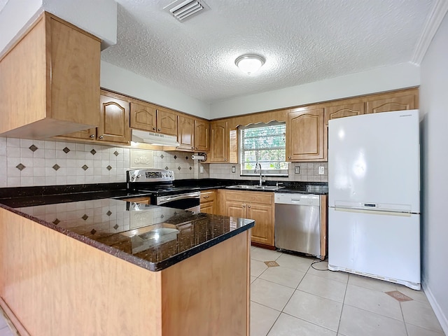 kitchen featuring sink, light tile patterned floors, dark stone countertops, kitchen peninsula, and stainless steel appliances