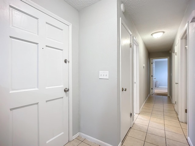 hall featuring a textured ceiling and light tile patterned floors