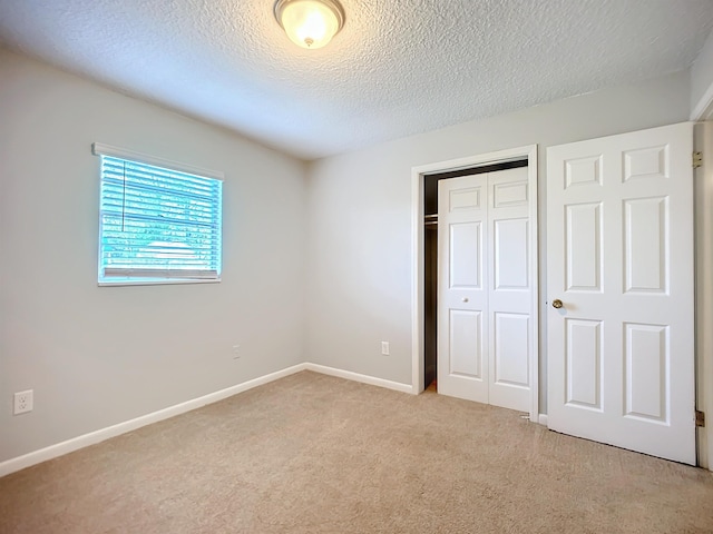 unfurnished bedroom featuring light carpet, a textured ceiling, and a closet