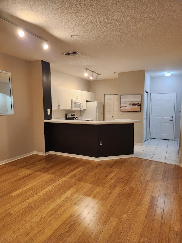 kitchen with white cabinetry, rail lighting, kitchen peninsula, a textured ceiling, and white appliances