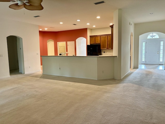 5850 Cypress Estates Dr, Elkton, FL 32033 - kitchen featuring freestanding refrigerator, arched walkways, light carpet, brown cabinets, and recessed lighting