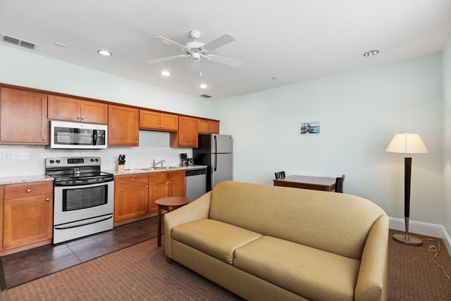 kitchen with dark tile patterned floors, a sink, visible vents, appliances with stainless steel finishes, and brown cabinetry