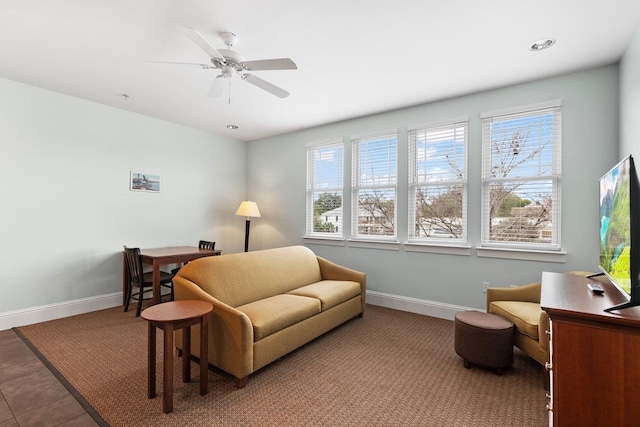 living area with a ceiling fan and baseboards