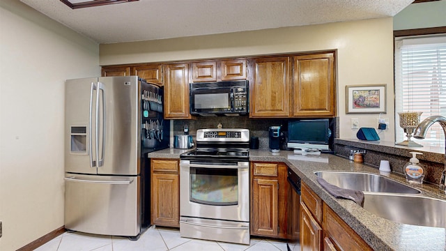 kitchen with appliances with stainless steel finishes, backsplash, a textured ceiling, sink, and light tile patterned floors