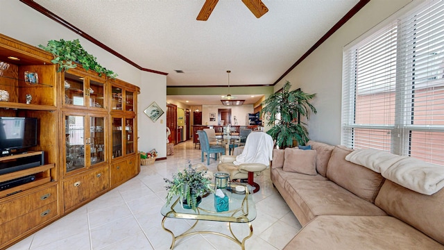 tiled living room featuring ceiling fan, ornamental molding, and a textured ceiling