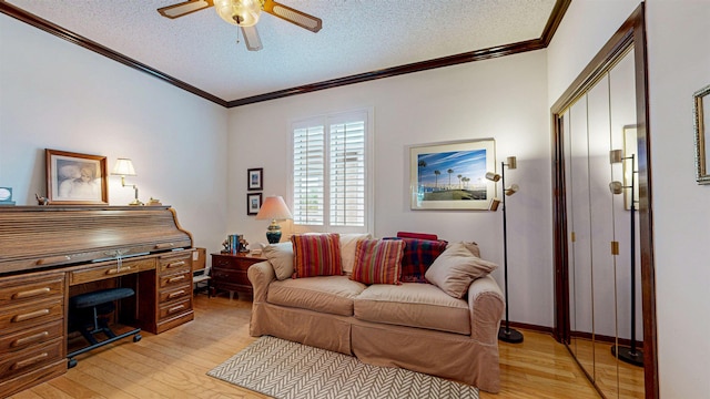 living room with ceiling fan, ornamental molding, a textured ceiling, and light wood-type flooring