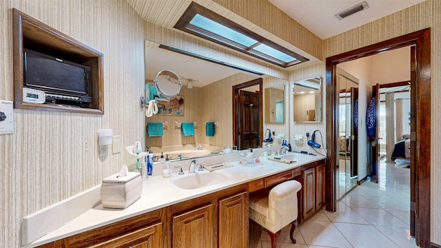 bathroom with tile patterned flooring, vanity, and a skylight