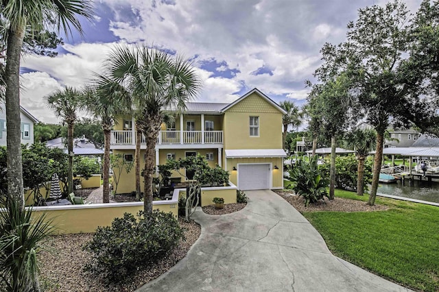 view of front of property with a garage, a balcony, a water view, and a front lawn