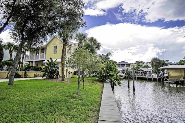 view of dock with a balcony, a water view, and a lawn