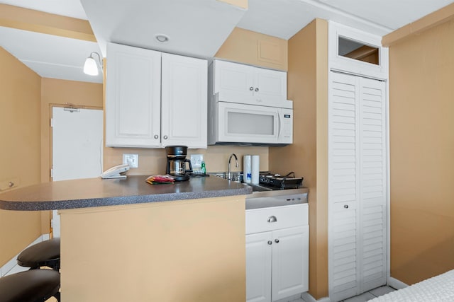 kitchen featuring a breakfast bar, sink, white cabinets, and kitchen peninsula