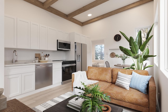 53 Hernandez Ave, Palm Coast, FL 32137 - kitchen with stainless steel appliances, a sink, beam ceiling, light wood-style flooring, and white cabinetry