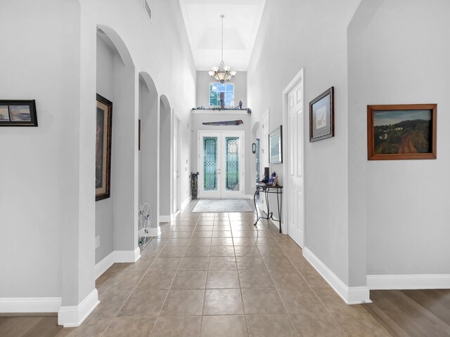 1201 Ellington Ct, Saint Augustine, FL 32084 - hallway featuring a chandelier, arched walkways, a towering ceiling, and light tile patterned flooring