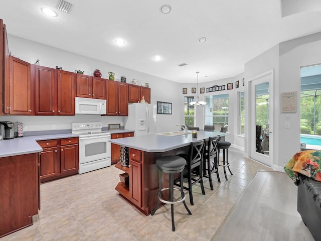 1201 Ellington Ct, Saint Augustine, FL 32084 - kitchen with white appliances, a breakfast bar, light countertops, a center island with sink, and hanging light fixtures