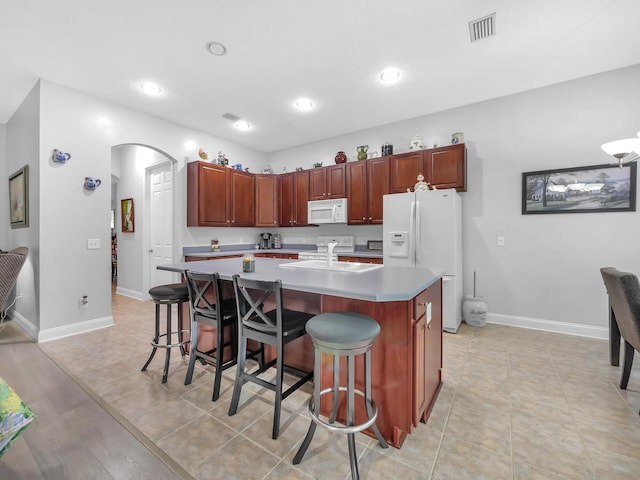 1201 Ellington Ct, Saint Augustine, FL 32084 - kitchen featuring white appliances, arched walkways, a breakfast bar area, a kitchen island with sink, and recessed lighting