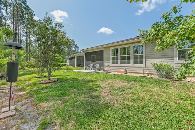 rear view of house with a lawn, a patio, and a sunroom