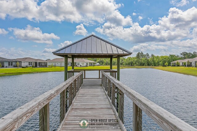 view of dock featuring a water view, a gazebo, a lawn, and a residential view