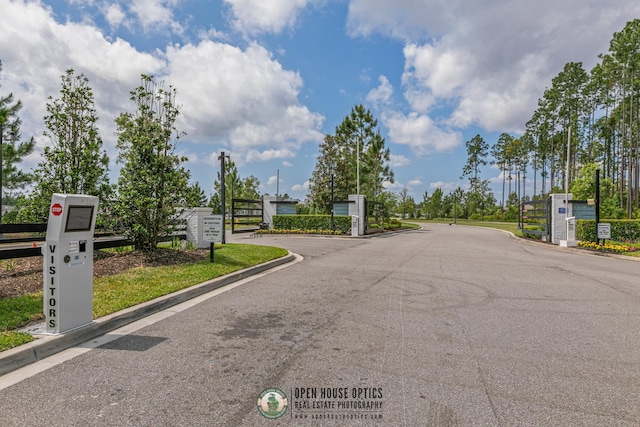 view of street featuring a gated entry, a gate, and curbs