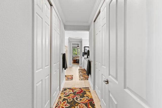 corridor with crown molding, light tile patterned floors, and baseboards