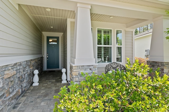 entrance to property featuring a porch and stone siding