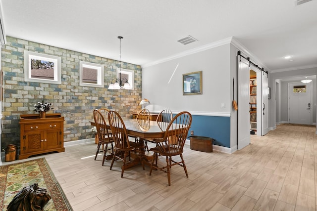 dining room with visible vents, a barn door, baseboards, ornamental molding, and light wood-style flooring