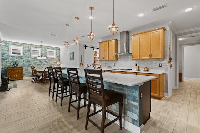 kitchen with gas cooktop, backsplash, visible vents, wall chimney exhaust hood, and light wood-style flooring