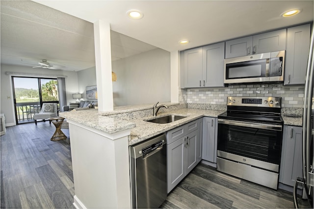 kitchen featuring kitchen peninsula, sink, stainless steel appliances, and dark wood-type flooring