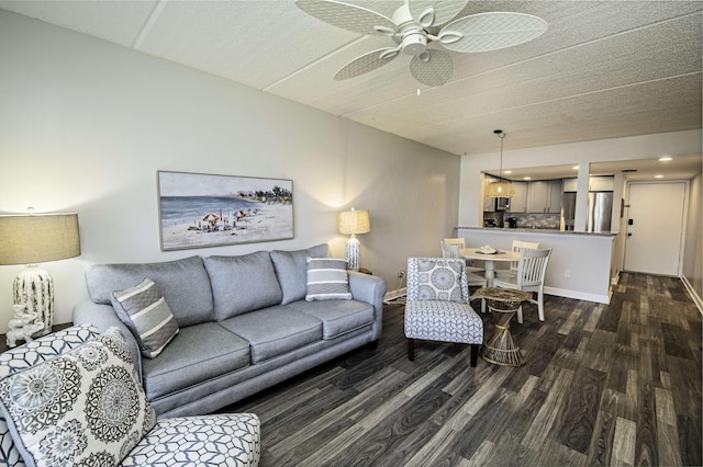 living room with a textured ceiling, dark hardwood / wood-style floors, and ceiling fan